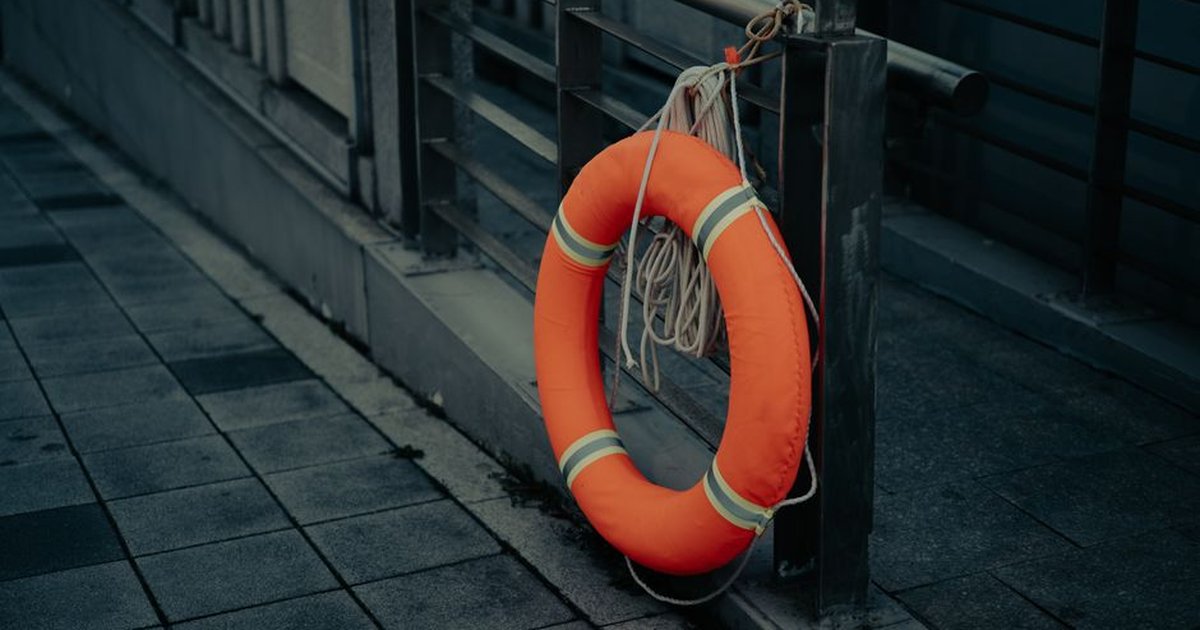An orange lifebuoy hangs on a railing along a tiled urban walkway in Shanghai.