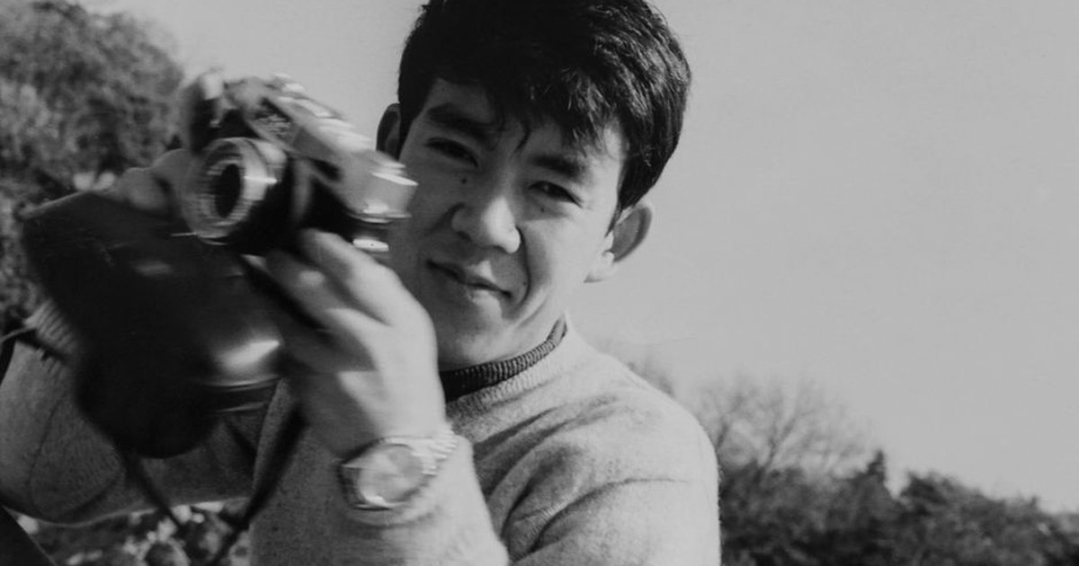 Black and white outdoor portrait of a male photographer holding a classic camera in Japan.