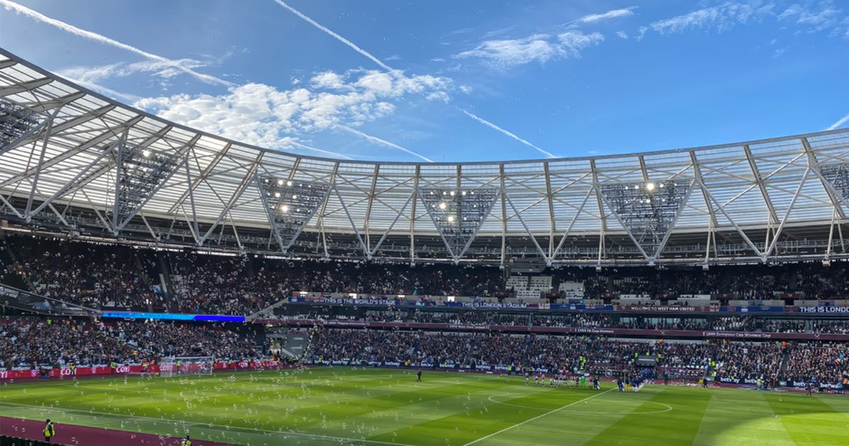 A packed London Stadium hosts a thrilling soccer match, with vibrant atmosphere and engaged crowd.