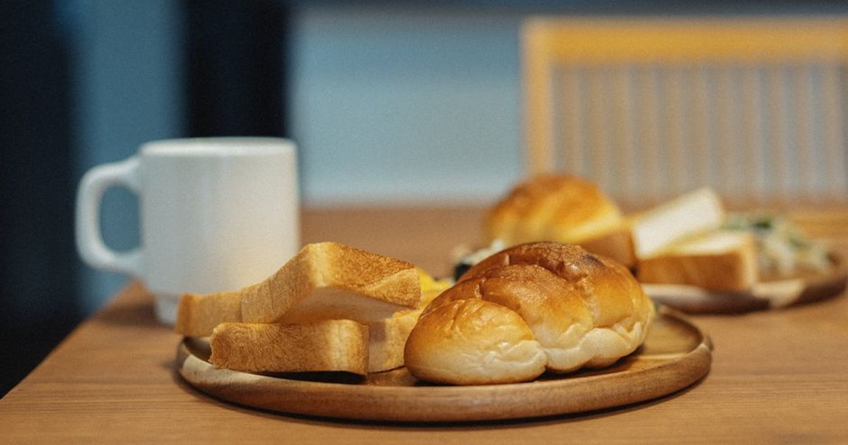 Warm morning setup of Japanese bread and coffee on a wooden table.