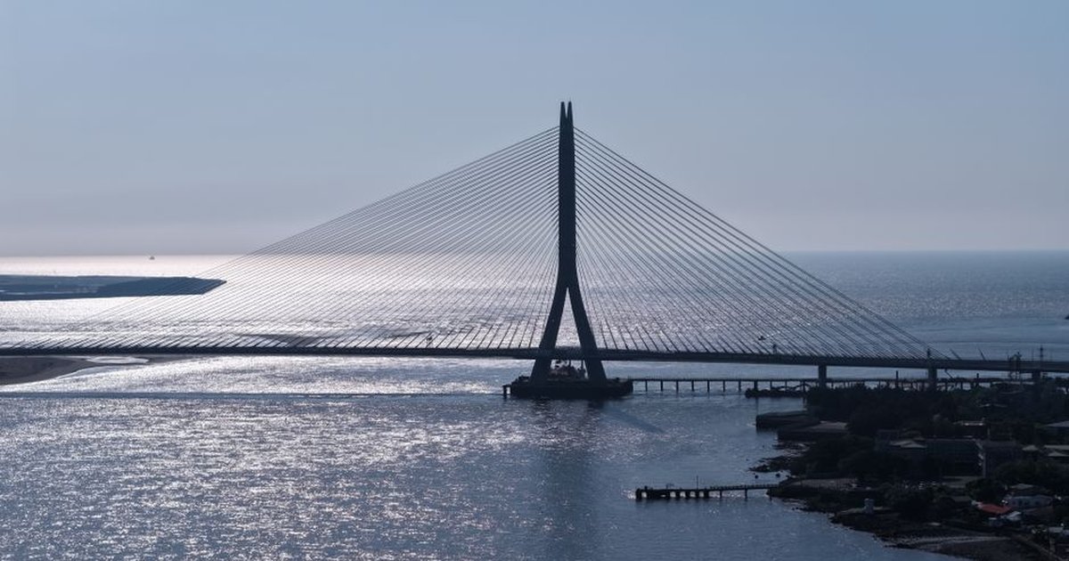 A stunning aerial view of the Tamsui River Bridge in Taipei, capturing its modern design against a shimmering sea backdrop.