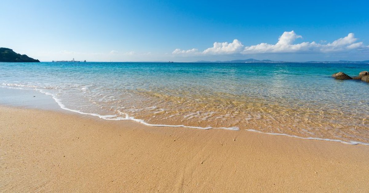 A serene beach scene with golden sands, clear waters, and blue skies, perfect for relaxation and nature appreciation.