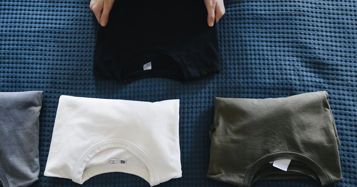 Top view of neatly folded colored T-shirts laid out on a blue bedspread, perfect for housekeeping themes.