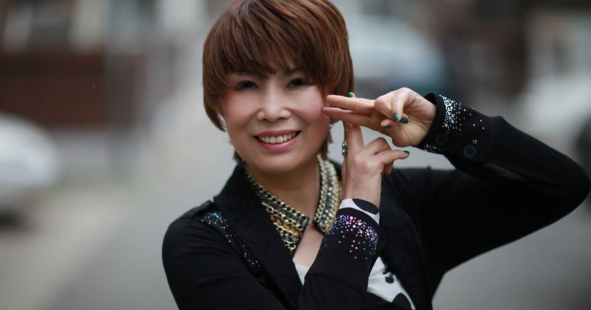 Smiling woman capturing a joyful moment with an expressive pose outdoors.