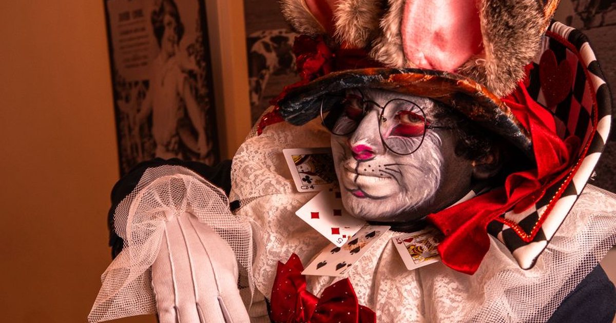 A captivating cosplay featuring a Mad Hatter inspired character with vibrant colors and playing cards.