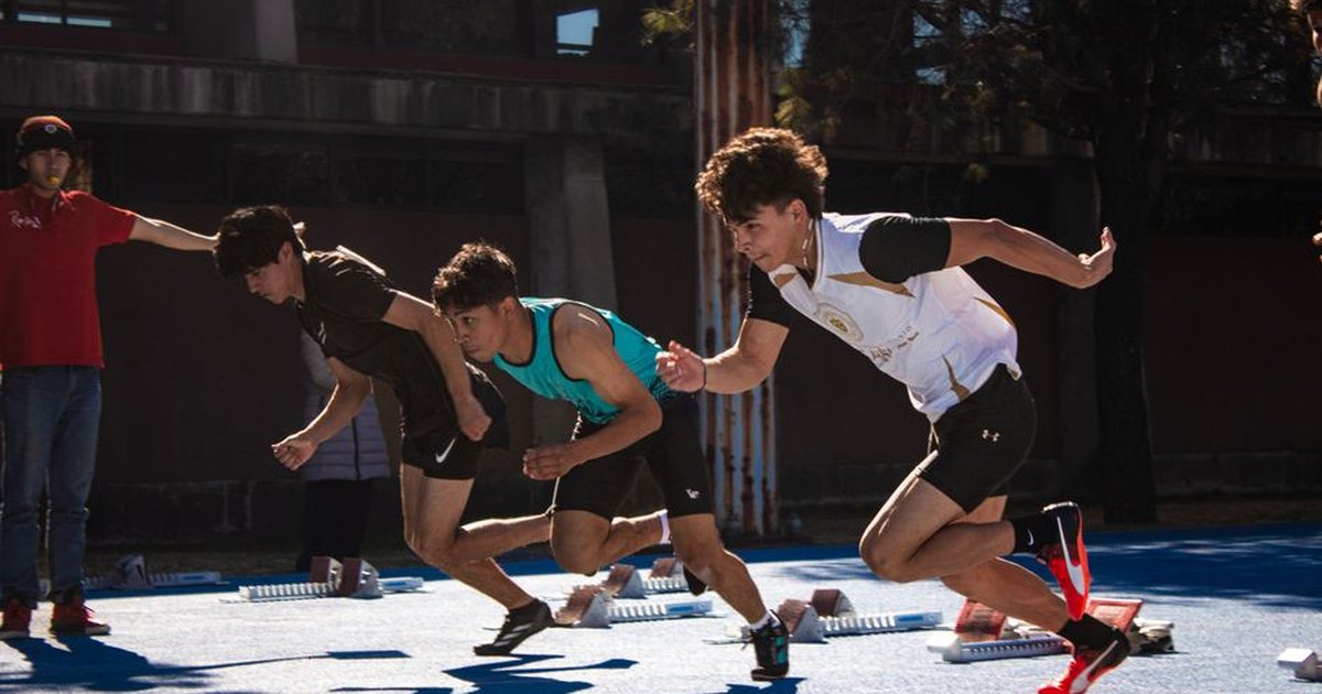 Dynamic action of male athletes sprinting from starting blocks on an outdoor track.
