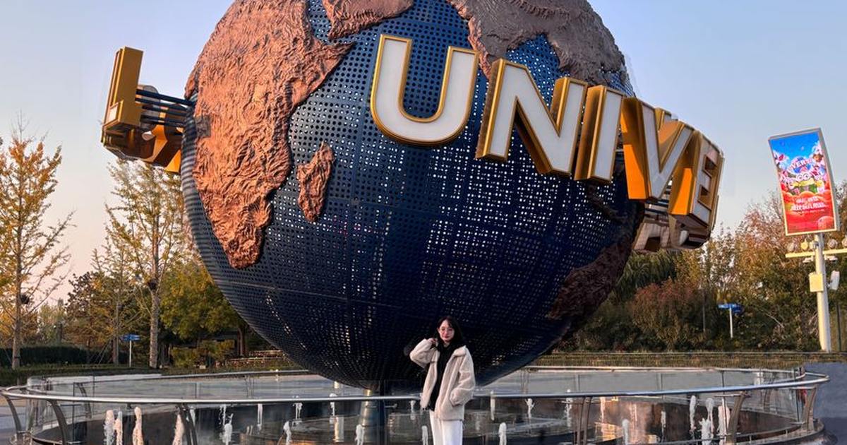A person poses in front of the iconic Universal Studios globe during sunset.