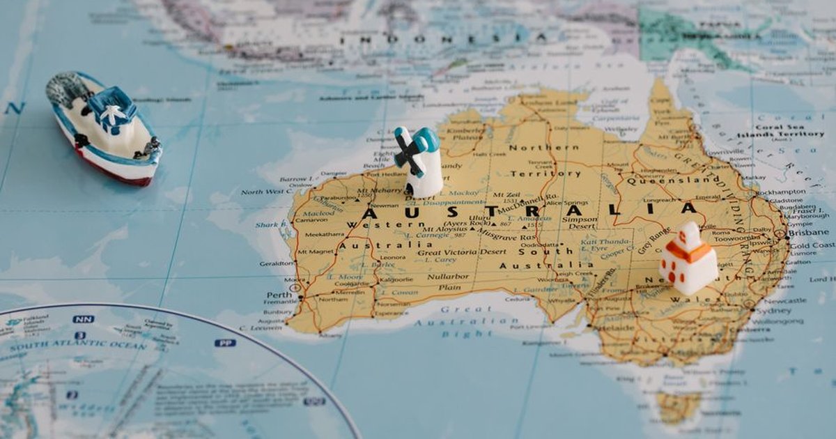 Miniature windmill and ship placed atop a map of Australia, highlighting travel concepts.