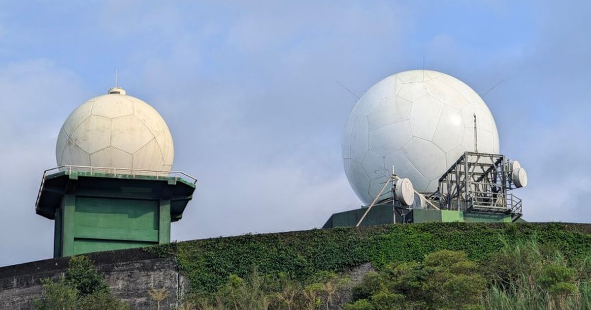 Radar domes on a lush hill in New Taipei City, Taiwan, contrasting technology with nature.