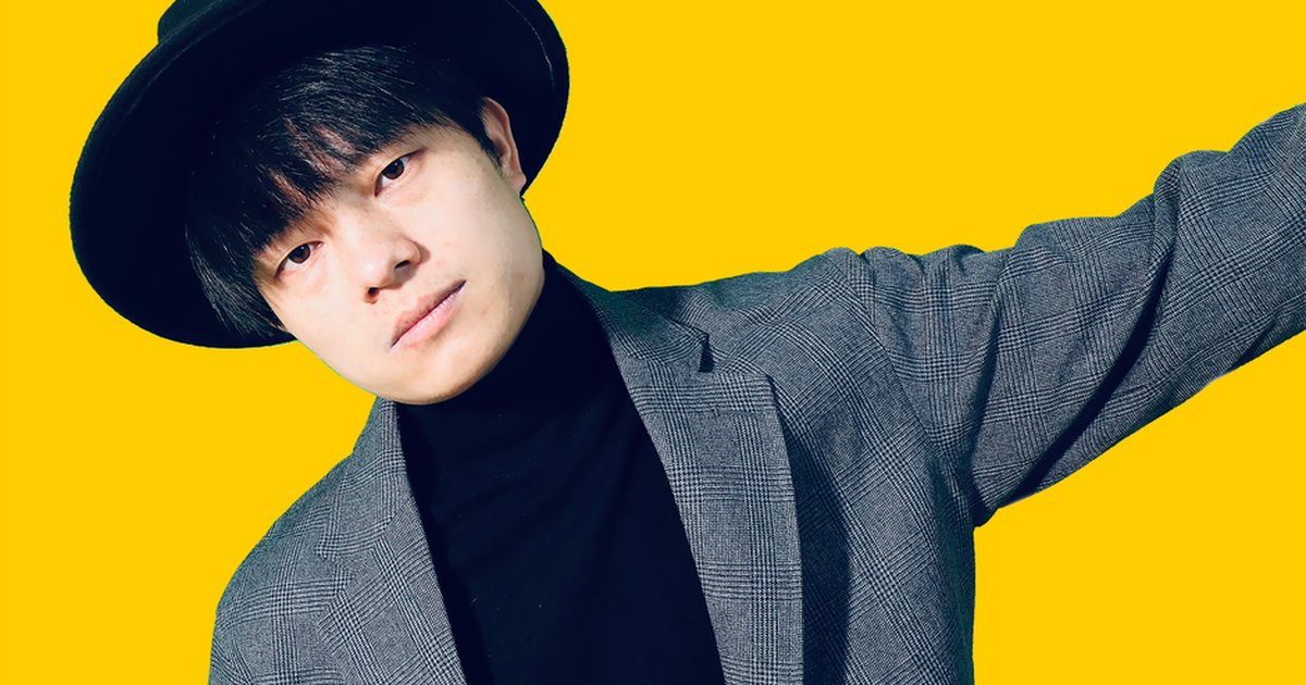 Stylish man wearing a black hat and blazer against a vibrant yellow background.
