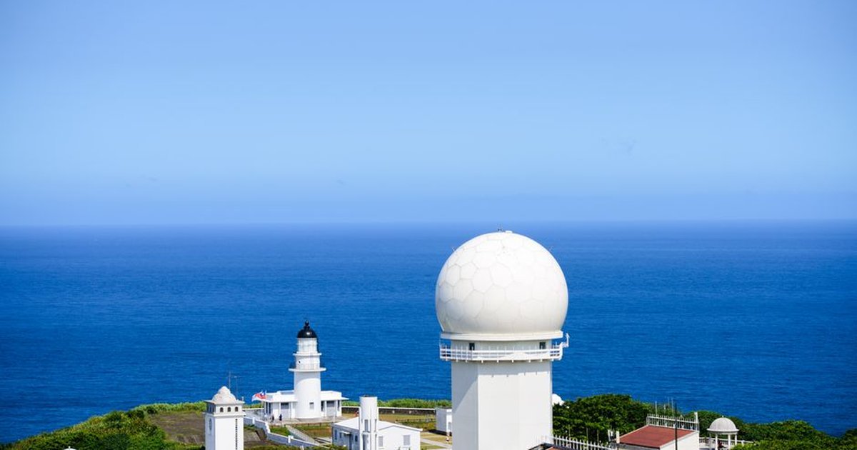 Stunning aerial shot of Sandiaojiao Lighthouse against a clear blue sky and expansive ocean.