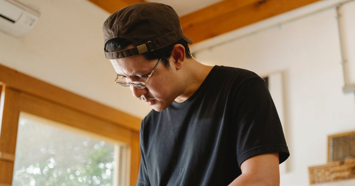 From below of pensive focused ethnic male in eyeglasses and cap doing job in modern workroom