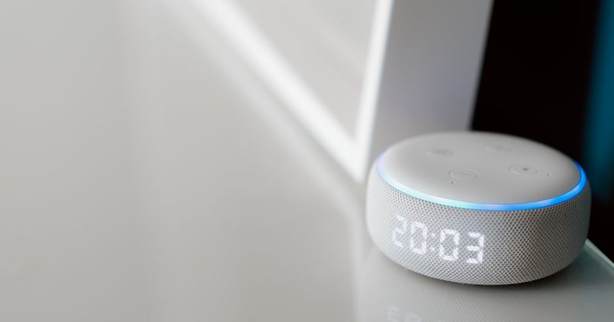 Close-up of a smart speaker with a digital clock display on a minimalist surface.