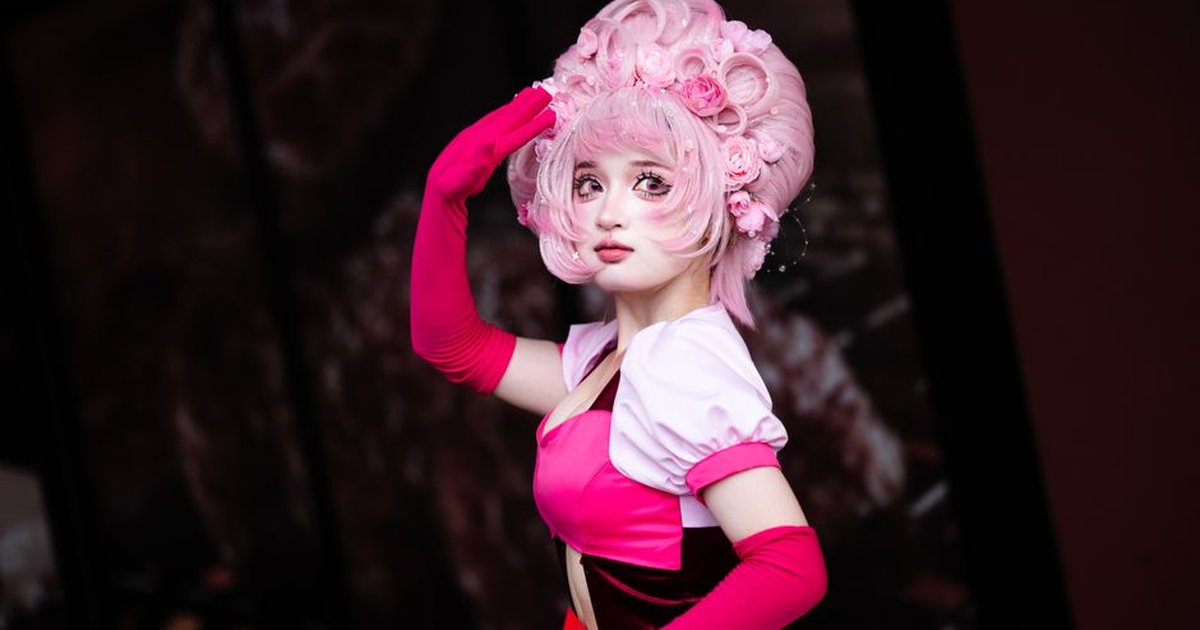 Cosplay portrait of a woman with pink hair and vintage style outfit.